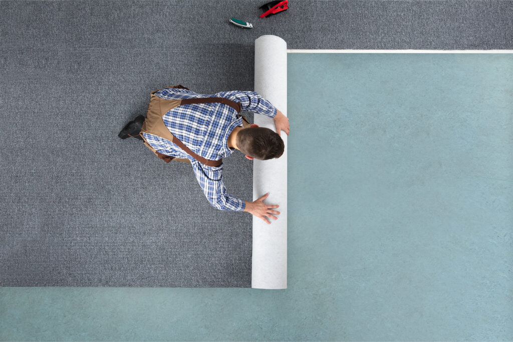 Man rolls out carpet for installation | Carpetland USA Wisconsin